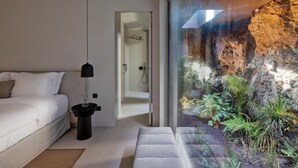 A modern bedroom with a large window overlooking a rocky garden. - Villa in Mykonos with 5 bedrooms sleeps 10 (Mykonos)
