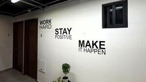 Een hal met aan de muur inspirerende kunst, een potplant en een plafondventilator.
