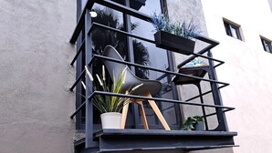 Een balkon met een stoel, plantenpotten en een raam.