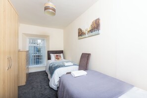 Un dormitorio con cama, armario, ventana con vistas y un cuadro en la pared.