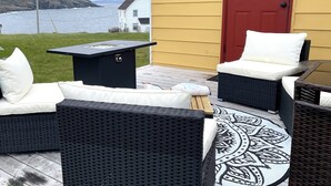 A patio with wicker furniture, a fire pit, and a view of the sea.