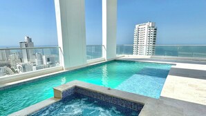A rooftop pool with clear blue water, a hot tub, and a city view. - Home Beach MagnoLoft (Cartagena)
