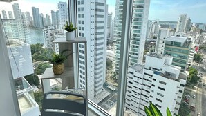 A modern room with large windows offering a city view, a glass table, and a chair. - Home Beach MagnoLoft (Cartagena)