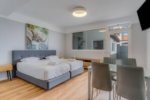 Une chambre d’hôtel moderne, dotée d’un grand lit, d’un bureau et d’une télévision.