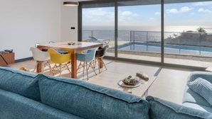 A modern living room with a large window overlooking a pool and a cityscape. - Casa Mozart II 15B in Estreito da Calheta (Calheta)