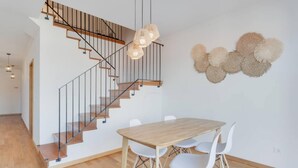 Un intérieur moderne avec un escalier en bois, une table à manger avec des chaises et un élément décoratif fixé au mur.
