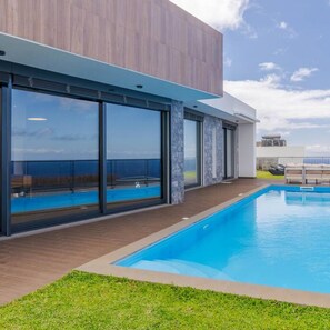 A modern building with a swimming pool, large windows, and a view of the sea. - Casa Mozart I in Estreito da Calheta (Calheta)