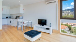 Un appartement moderne doté d’une cuisine, d’un coin repas et d’une grande fenêtre offrant une vue sur la ville.