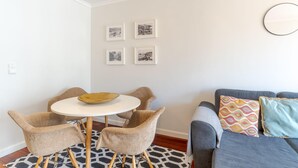 Una sala de estar con una mesa redonda, dos sillas, un sofá y un tapete estampado.