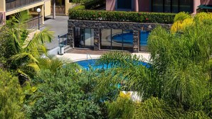 A hotel with a pool surrounded by lush greenery and a multi-story building with balconies. - Santa Luzia Funchal View 2 Bedrooms Pool (Funchal)