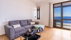 A modern living room with a grey sofa, a black coffee table, and a large window offering a view of the sea. - Monumental Apartment 712 Balcony Sea View (Funchal)