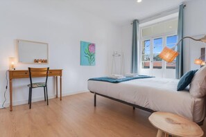 Une chambre à coucher avec un lit, un bureau, une chaise, une lampe et un tableau au mur.