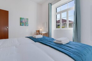 Une chambre d’hôtel avec un lit, un bureau et une fenêtre avec des rideaux.