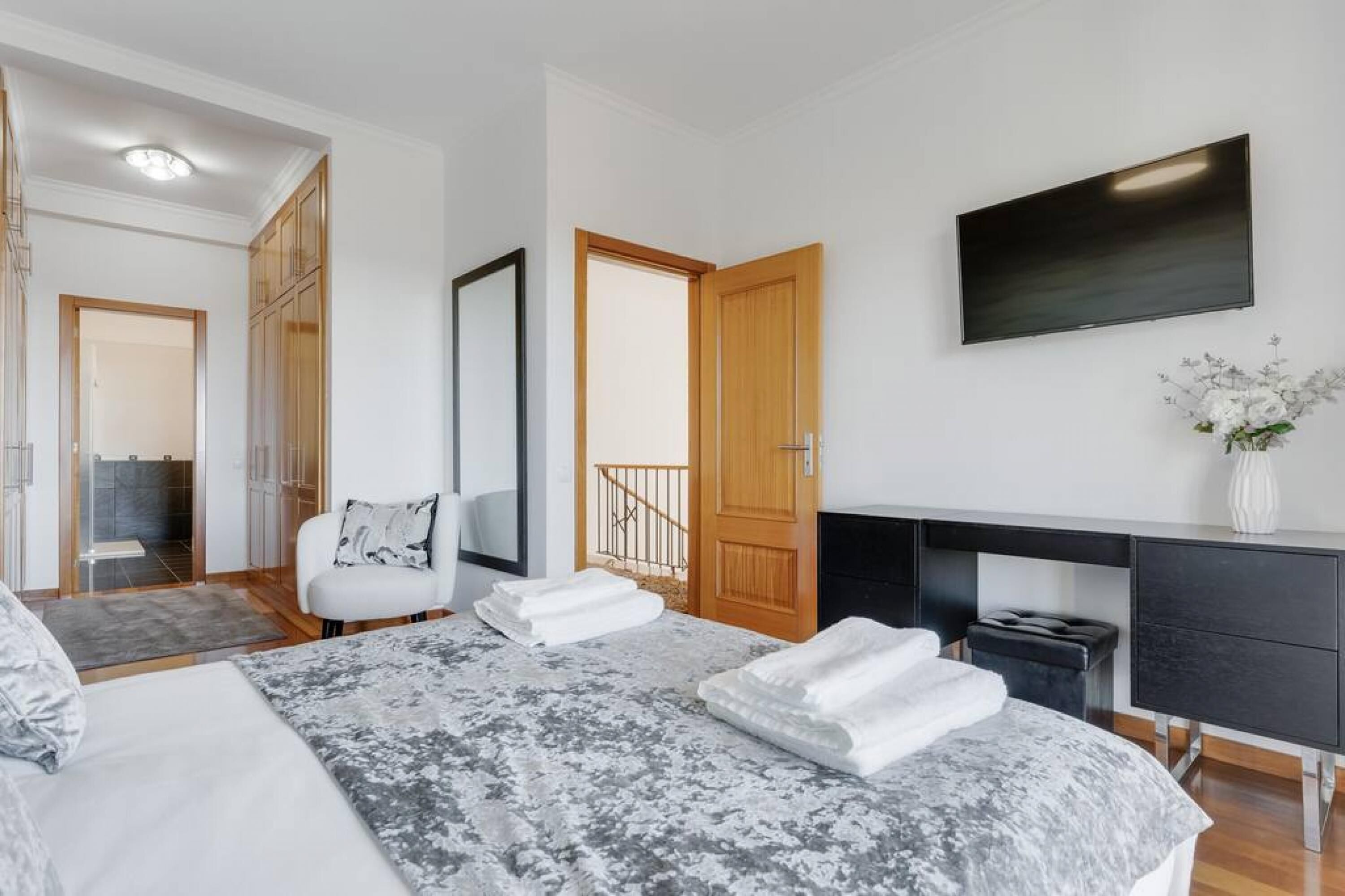 A modern bedroom with a large bed, a desk, and a TV.