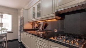 Een moderne keuken met witte kasten, een zwart aanrecht, roestvrijstalen apparatuur en een gasfornuis.