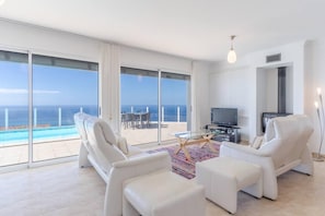 A spacious living room with a large sliding glass door leading to a balcony with a pool view. - Villa Eldomar 61 in Estreito da Calheta (Calheta)