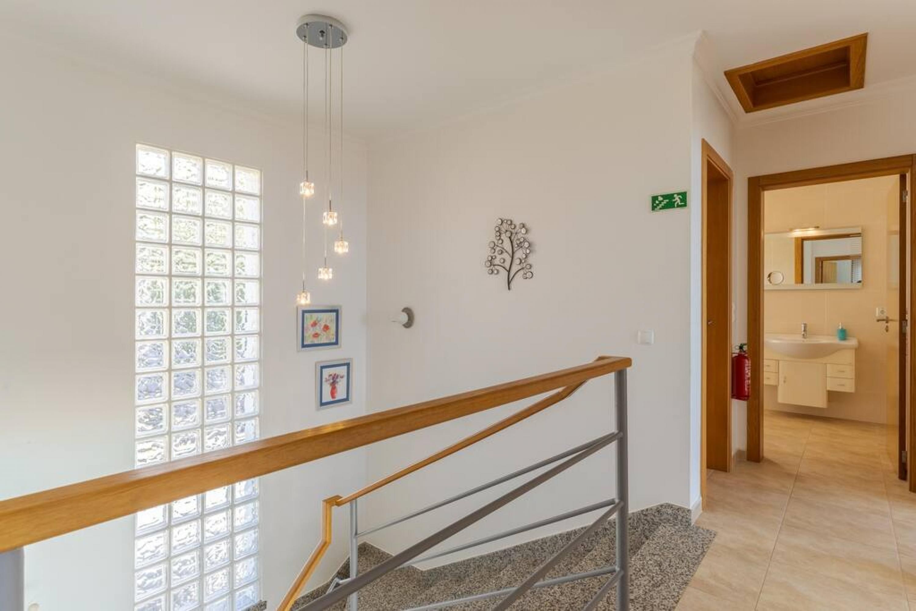 A staircase with a wooden handrail, a wall-mounted light fixture, and a window with frosted glass panels.