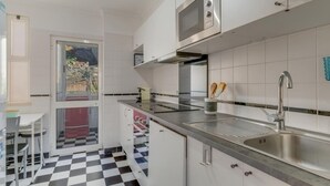 A modern kitchen with white cabinets, a stainless steel sink, and a microwave. - Ajuda I 4 D in Funchal (Funchal)