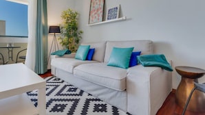 A modern living room with a white sofa, teal cushions, a patterned rug, and a small side table. - Ajuda I 4 D in Funchal (Funchal)