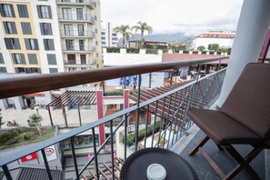 A balcony with a view of a cityscape, including buildings and palm trees. - Forum Madeira Ocean View 4B (Funchal)