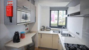 Ett modernt kök med ett fönster, en diskho, en spis och en kaffemaskin.