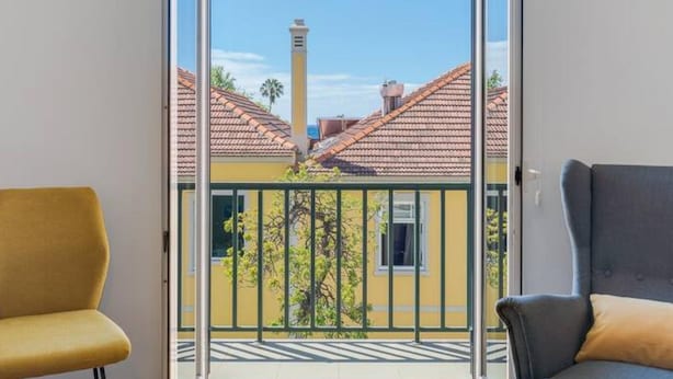 En balkon med frit udsyn til omkringliggende bygninger og en skorsten.
