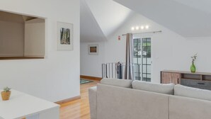 A modern living room with a large sectional sofa, a wooden floor, and a sloped ceiling. - Encanto em Santa Cruz (Santa Cruz)