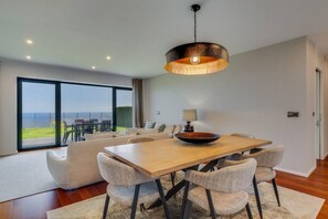 A modern dining area with a wooden table, woven chairs, and a large pendant light. - Mango in Funchal With 2 Bedrooms and 2 Bathrooms (Funchal)