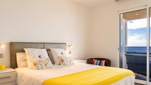 Un dormitorio con cama, mesita de noche, una silla y un balcón con vistas.