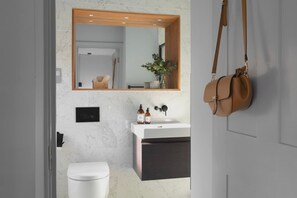 Un bagno moderno con un lavandino in marmo, un water bianco e uno specchio con cornice in legno.