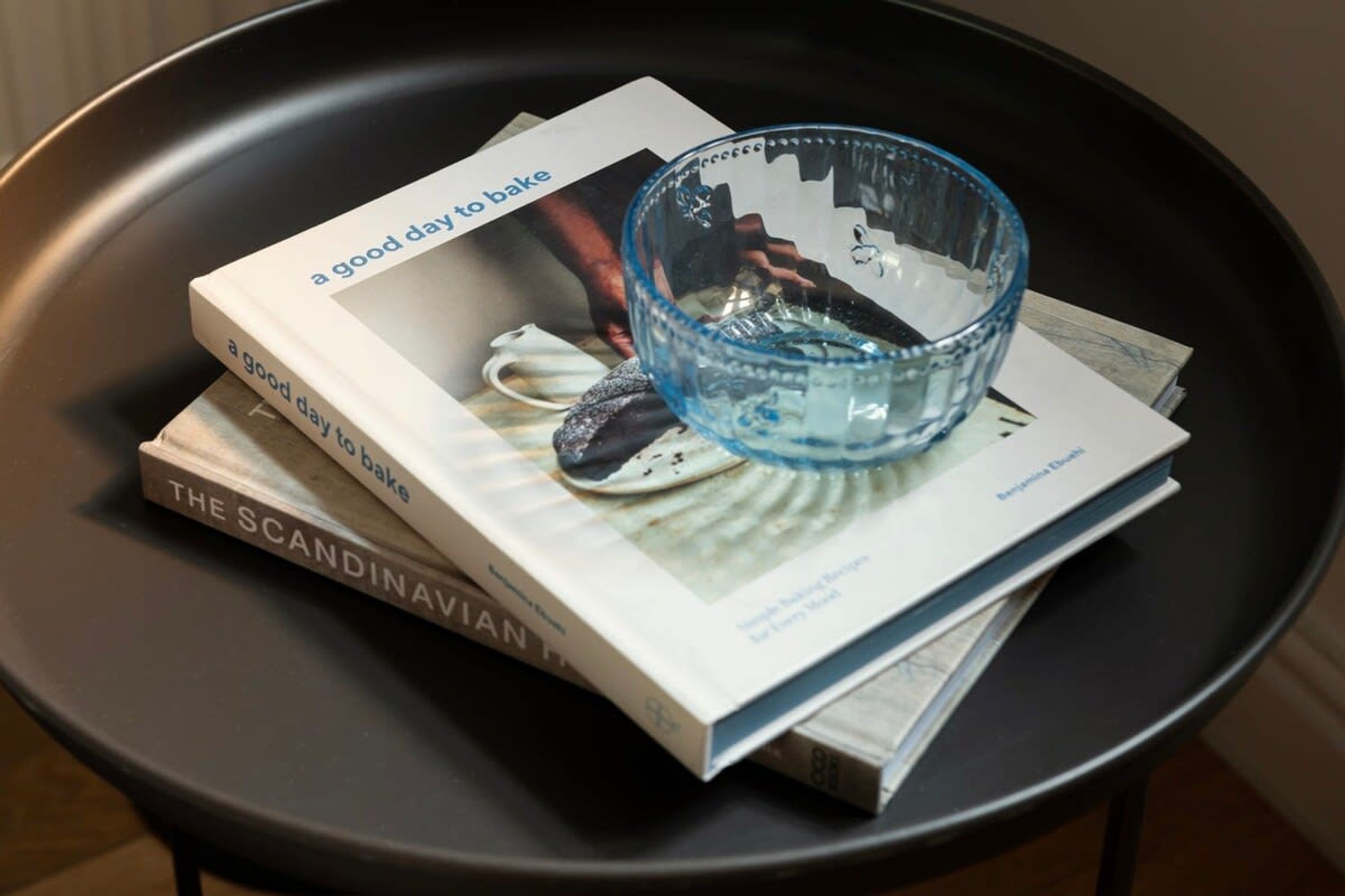Ein Buch mit dem Titel „The Scandinavian Kitchen“ und eine blaue Glaskugel auf einem schwarzen Tisch.