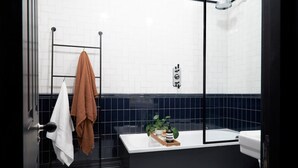 A modern bathroom with a bathtub, a glass shower enclosure, and a towel rack with a brown towel. - Contemporary Studio - Minutes From Angel Tube St (London)