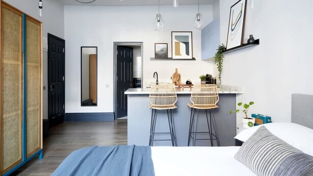 A modern bedroom with a large bed, a bedside table, and a nightstand. There is a window with a view of the outside. - Contemporary Studio - Minutes From Angel Tube St (London)