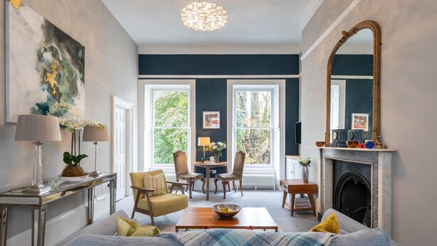 Ein Wohnzimmer mit einer Couch, Sesseln, einem Couchtisch, einem Kamin und einem großen Spiegel.