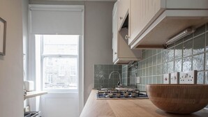 Cozinha moderna com uma janela ampla, uma tigela de madeira no balcão e painel de azulejos.
