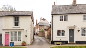 A narrow street with traditional houses, a pink door, and a mailbox. - Lavender Folly - Cosy Accommodation Alresford (Alresford)