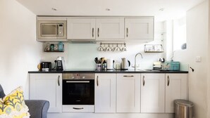 A compact kitchen with white cabinets, a microwave, a coffee maker, and a sink. - Lavender Folly - Cosy Accommodation Alresford (Alresford)