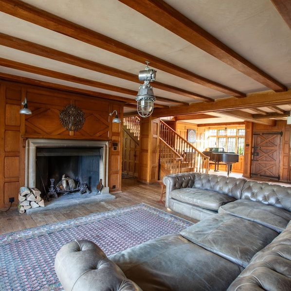 A spacious living room with a fireplace, leather sofa, and a staircase leading to another level.