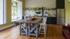 A spacious kitchen with a wooden table, white chairs, and a brick backsplash. - Large Country House in Ashdown Forest (East Grinstead)