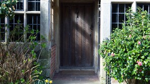 A building with a stone facade, a wooden door, and a tiled roof. - Large Country House in Ashdown Forest (East Grinstead)