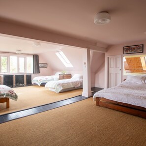 Une chambre avec deux lits, un puits de lumière, un radiateur et une grande fenêtre.