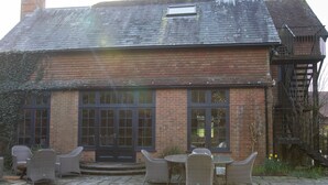 A brick house with a large front porch, a chimney, and a staircase leading to an upper level. - Large Country House in Ashdown Forest (East Grinstead)