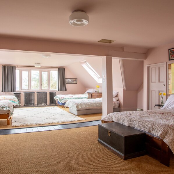 Une chambre avec deux lits, une grande fenêtre, un radiateur et un puits de lumière.
