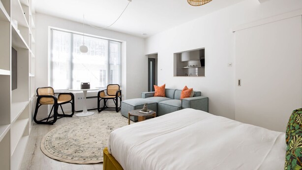 A modern bedroom with a bed, a sofa, a desk, and a chair. - Light-filled Studio With AC - Earl s Court (London)