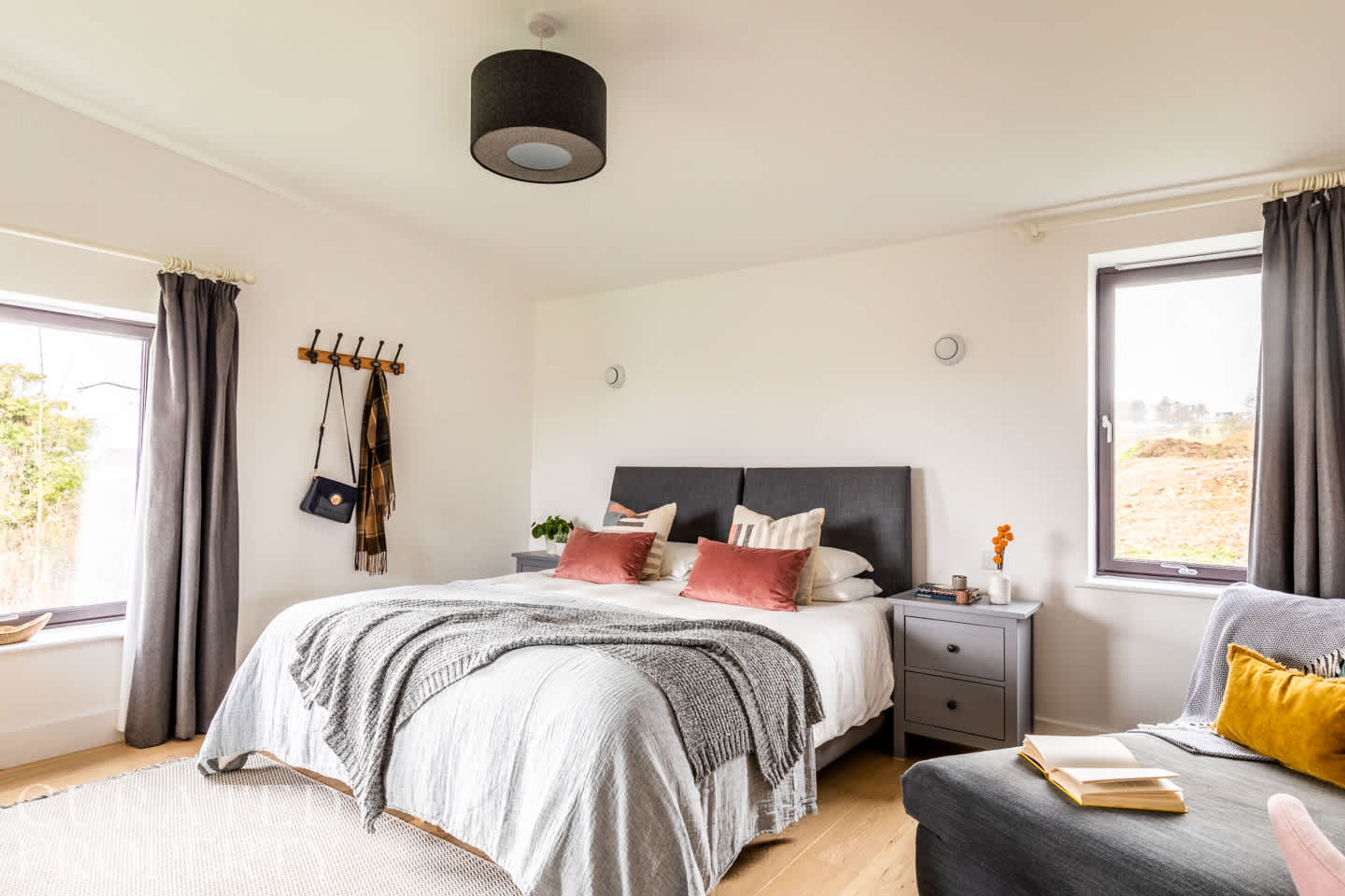 Een slaapkamer met een bed, nachtkastje en een raam met gordijnen.