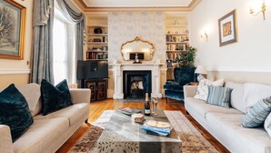 Een ruime woonkamer met twee banken, een open haard, boekenkasten en een televisie.