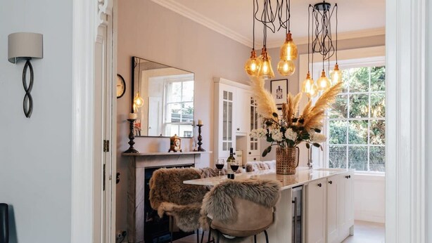 Een moderne keuken met een centraal eiland, hanglampen en uitzicht op de omgeving.