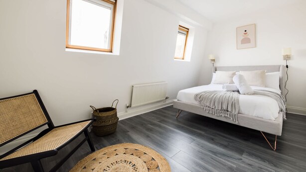 Une chambre à coucher avec un lit, une chaise, une fen être et un radiateur.