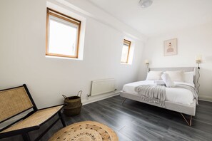 Une chambre à coucher avec un lit, une chaise, une fenêtre et un radiateur.