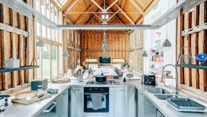 A spacious kitchen with a central island, stainless steel appliances, and wooden beams. - Grand Suffolk Barn Conversion (Ipswich)